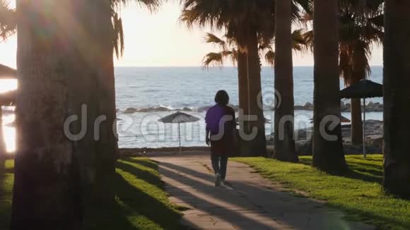 穿着休闲装去海滩的年轻女孩布鲁内特女士步行去海滩女孩用手掌沿着旅游区散步女人走路视频的预览图