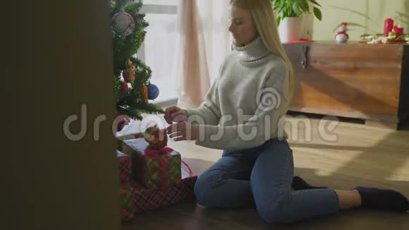 漂亮的女人在窗户边用玩具装饰圣诞树视频的预览图
