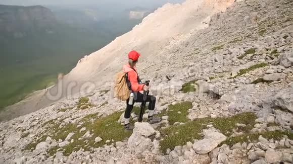 一位年轻的摄影师站在山腰上站在高原悬崖峭壁的背景下视频的预览图