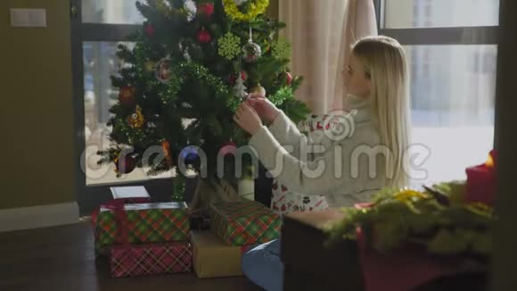 穿毛衣的漂亮女孩用黄球装饰圣诞树很漂亮的圣诞内饰视频的预览图