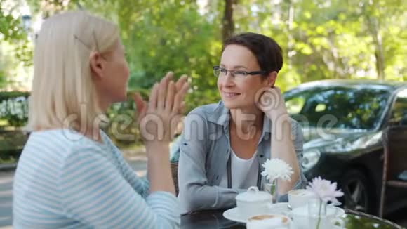 快乐的朋友女士们享受夏日户外咖啡馆的谈话视频的预览图