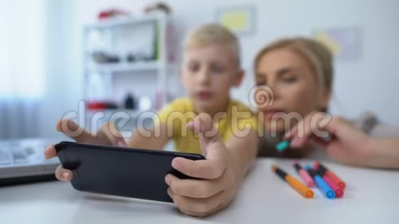 小男孩玩新手机游戏妈妈给儿子小费消遣视频的预览图