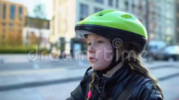 坐在自行车上戴着运动头盔的专心致志的小女孩准备骑户外运动视频的预览图