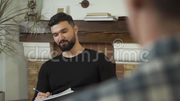 一个成年白种人坐在报纸上说话微笑的特写脸专业男性心理学家视频的预览图