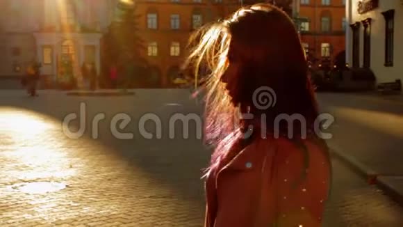 女孩在一条城市街道上摆姿势阳光温暖黄色的橙色秋日视频的预览图