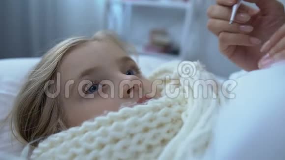 母亲用手把电子体温计放进女儿的嘴里流行病健康视频的预览图