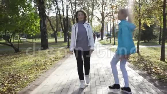 年轻貌美的白种人祖母和十几岁的孙女穿着休闲装在夏季公园散步视频的预览图