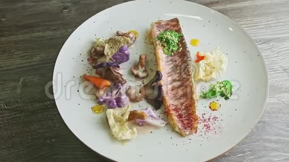 时尚装饰的烤鱼片和切好的蔬菜在盘子上旋转视频的预览图
