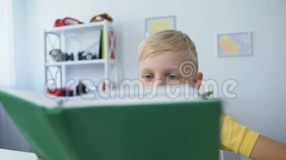疲倦的小男孩阅读教科书把头放在桌子上教育理念视频的预览图