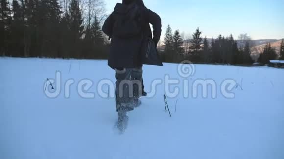 在森林边缘的雪地草坪上慢跑的不可辨认的家伙的后景年轻人在雪地上奔跑视频的预览图