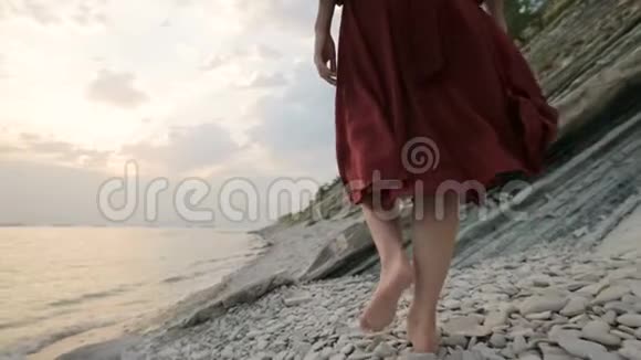 光着脚的女孩带着波浪走在沙滩上穿着白色衣服的非洲女孩光着脚在海边的海浪中行走视频的预览图