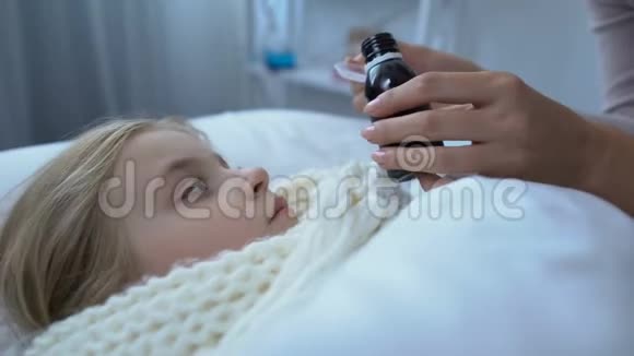 有爱心的女家长给躺在床上的生病的小女儿注射咳嗽糖浆流感视频的预览图