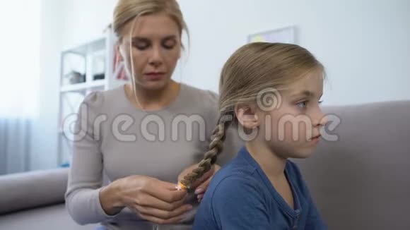 可爱的母亲编辫子梳漂亮女儿的头发家人视频的预览图