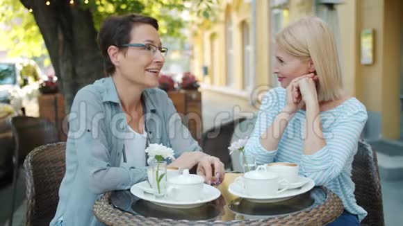 成熟的女士在户外咖啡馆里慢动作谈笑风生视频的预览图