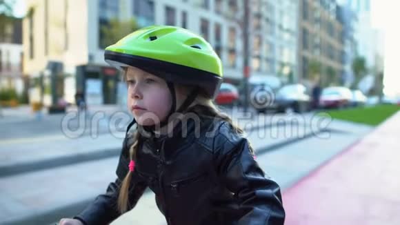 可爱的女孩子戴着安全帽坐在自行车上准备骑在街上视频的预览图