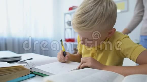 勤奋的男孩子在办公桌前做作业妈妈表扬儿子摸着头视频的预览图