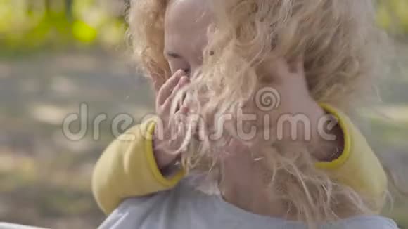 秋天公园里坐在长凳上的一位年轻的白种人女人卷发卷曲金发两个可爱的小女孩视频的预览图