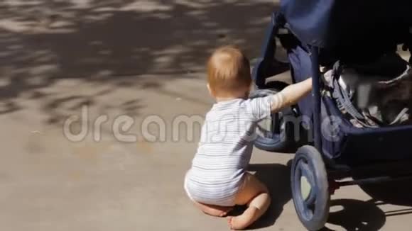 小男孩玩婴儿车的轮子来回摇晃它视频的预览图