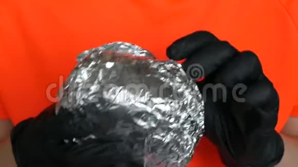 一个少年展开大箔汉堡双手戴专用黑色手套手拿垃圾食品快餐脸部和嘴巴靠近视频的预览图