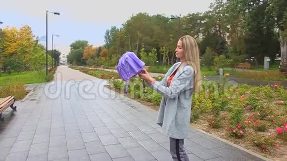女孩在雨中打开一把紫色的雨伞在公园散步然后走到远处视频的预览图
