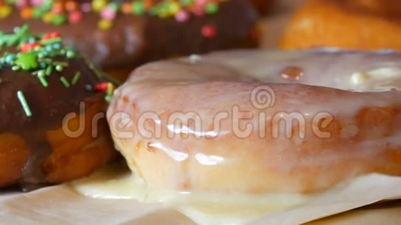 一张桌子上连续摆着许多五颜六色的新鲜油炸甜甜圈一个美丽的甜甜圈和白色的糖衣洒在视频的预览图