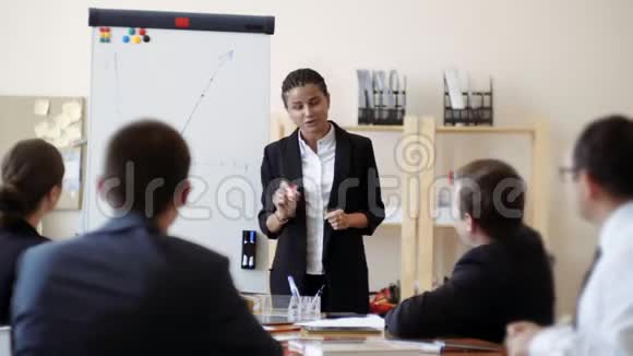 非裔美国女孩在白板上进行情绪展示并向办公室办公桌上的工作人员讲述计划视频的预览图