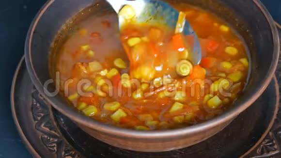 热的红番茄汤配玉米用汤匙放在一个棕色的土制盘子里视频的预览图