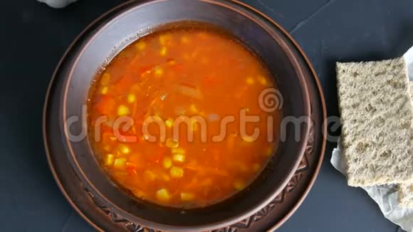 热红番茄素食汤蔬菜和玉米在一个黑色背景的粘土老式盘子的顶部视图视频的预览图