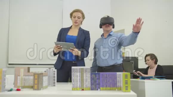 拿着平板电脑的建筑师在办公室里用虚拟眼镜告诉她的同事一些事情视频的预览图