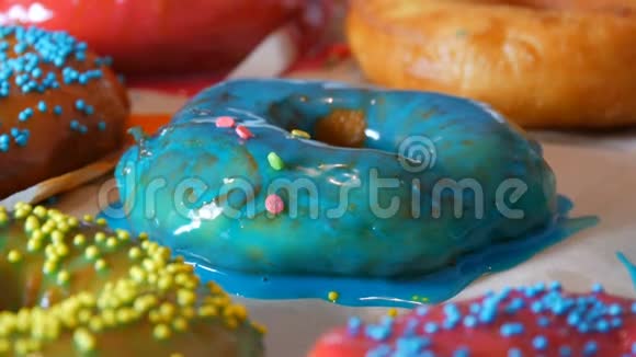大的多色鲜炸面圈排在一张桌子上一个美丽的甜甜圈和蓝色的糖衣洒在视频的预览图