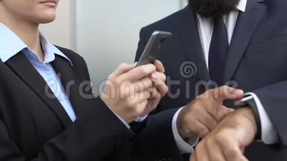 女经理在户外滚动智能手机男同事指着手表视频的预览图