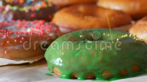 大的多色鲜炸面圈排在一张桌子上一个美丽的甜甜圈和绿色的糖霜洒在视频的预览图