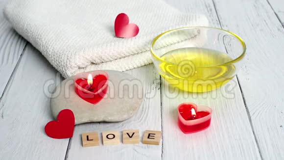 情人节水疗概念燃烧红色心形蜡烛石头按摩油爱情和白色毛巾视频的预览图