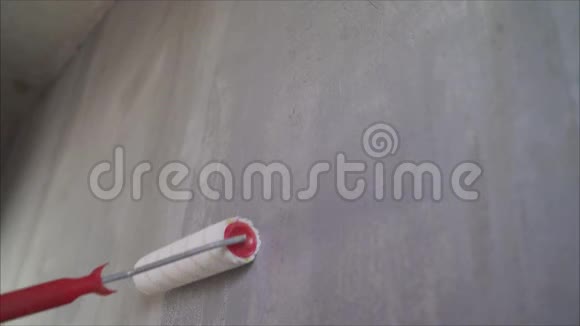 工人用长滚筒将底漆涂在墙上一只雄手正在用滚筒将底漆涂在白色的墙壁上湿湿视频的预览图