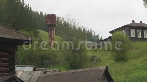 古老的俄罗斯村庄古老的木屋和绿色多汁的草地视频的预览图