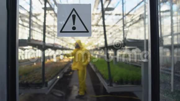 温室内防护制服冲洗植物的工人门上有警告标志视频的预览图
