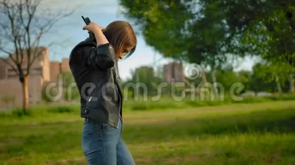 一个年轻的女人戴上黑色的大耳机打开智能手机上的音乐视频的预览图