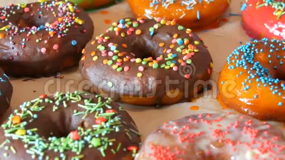 新鲜可口的圆形甜甜圈有多种颜色的巧克力糖衣粉色蓝色白色橙色绿色和各种装饰视频的预览图