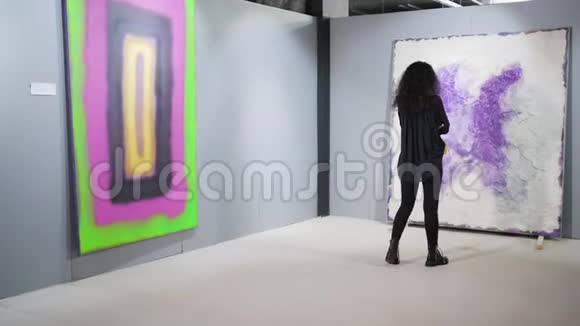 独身的黑发女子在美术馆观看抽象画面视频的预览图