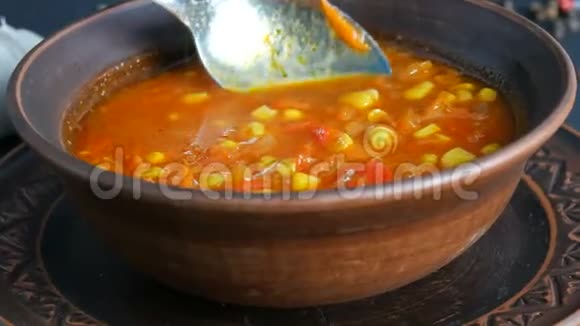 在黑色背景下的一个陶土盘子里将热红番茄素食汤与蔬菜和玉米混合在一起视频的预览图