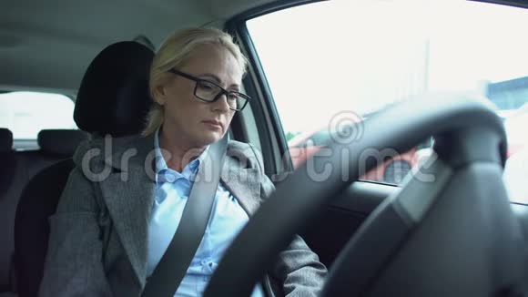 坐在司机车座上摸着头工作压力大的老年妇女心烦意乱视频的预览图