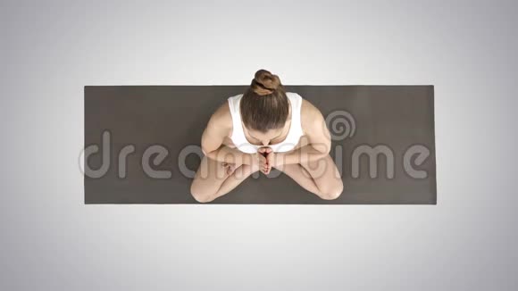 年轻的瑜伽女性练习瑜伽在莲花姿势中做Namaste手势在渐变背景上穿白色t恤视频的预览图