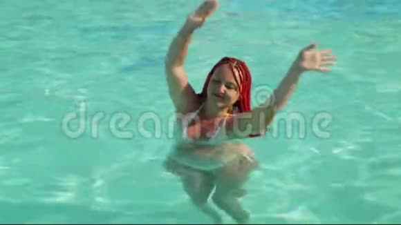 一个扎着辫子的晒黑的女人举起手在游泳池里跳舞视频的预览图