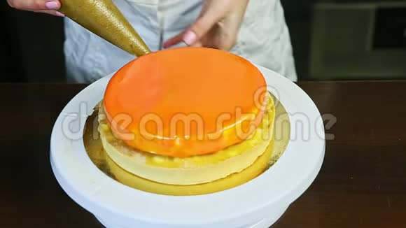 在白台上用橘色镜面釉装饰芝士蛋糕的工艺视频的预览图