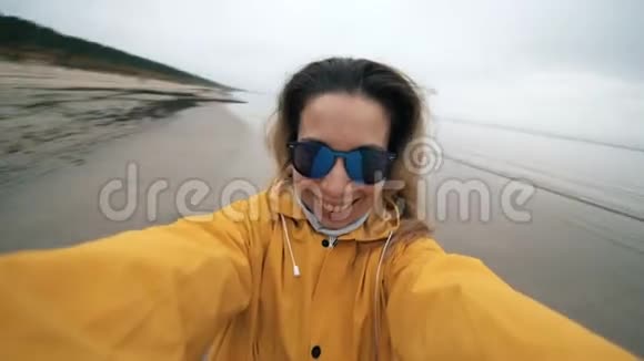 微笑的女人正在海岸拍摄自己视频的预览图