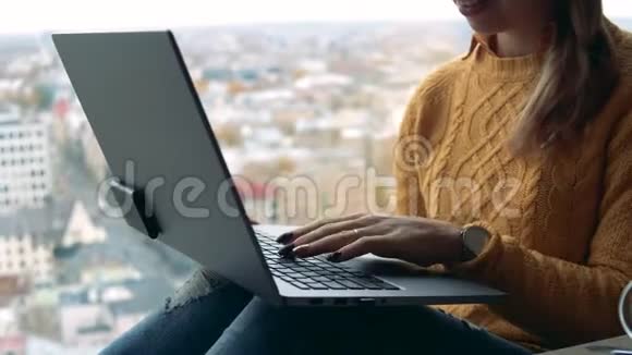一位商务女士在一台笔记本电脑上打字与城市景色相对照视频的预览图