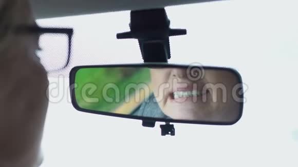 老年妇女在车镜里看牙齿按摩疼痛的脸颊牙齿护理视频的预览图