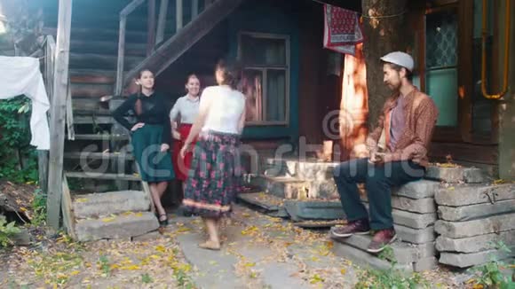 一个穿着五颜六色裙子的女人在音乐中跳舞和另一个女人聊天一个男人在演奏巴拉莱卡视频的预览图