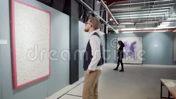 男性参观者正在参观现代抽象艺术家的绘画作品视频的预览图