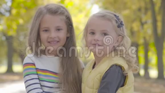 两个漂亮的小白种人姐妹站在秋天的公园里微笑着美丽可爱的女孩在一起视频的预览图